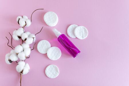 Facial tonic or makeup remover and cotton pads for face care on pink background top view, flat lay. Copy space.の写真素材