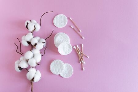 Cotton sticks and pads with fluffy cotton flowers on pink background top view. Flat lay. Copy space for your text.の写真素材