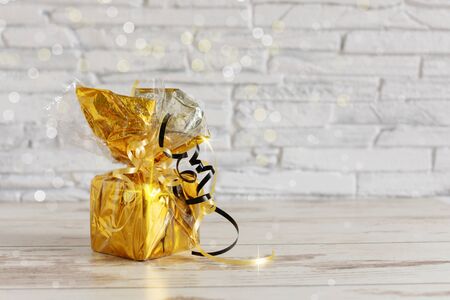 Golden gift box on colored background with bokeh. Holiday present concept. Copy space for your text.の写真素材