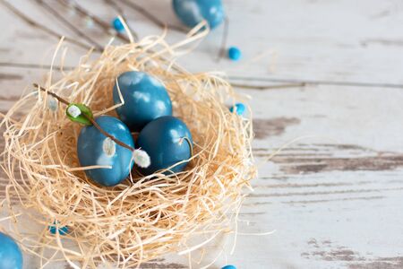 Easter eggs in a modern marble classic blue color in a nest on wooden table top view. Happy Easter time. Creative Easter decoration. Copy space.の写真素材