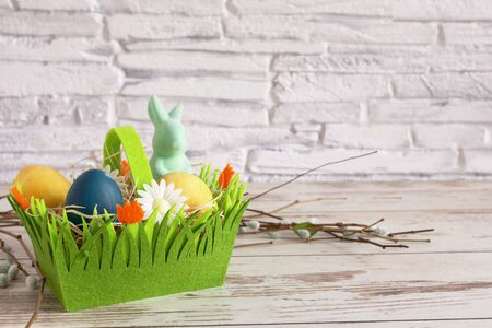 Colorful Easter eggs and Easter bunny in a green basket. Easter background. Happy Easter time. Copy space.の写真素材