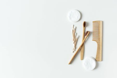 Two bio-degradable, compostable bamboo toothbrushes, hair brush and cotton pads on white background...