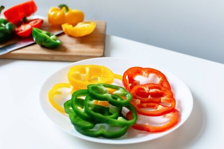 Set of colorful sliced bell pepper on plate on white background top view. Slices of red, yellow and...