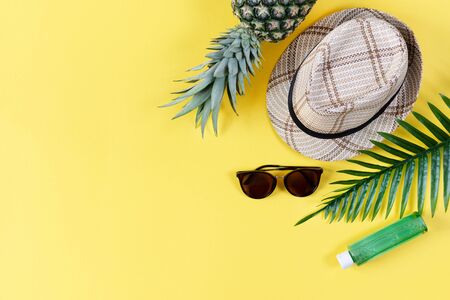 Colorful summer composition with straw hat, sunglasses, palm branche, pineapple and flip flops on yellow background top view. Summer fashion, vacation concept.の写真素材