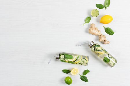 Detox infused water with lemon, lime, ginger and cucumber in a glass sport bottle on white wooden table top view. Detoxification. Healthy eating concept.の写真素材