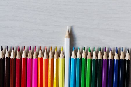 Row of colorful pencils on white wooden background top view. Education concept. Rainbow palette of...