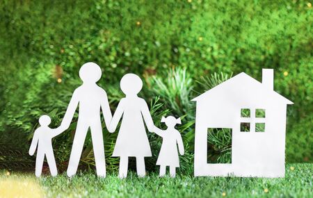 White paper cut of family with house on green grass background. Happy family concept.の写真素材