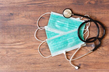 Medical mask for protection against cold and flu or other virus. Surgical protective mask top view. Medical respiratory bandage face on wooden background.の写真素材