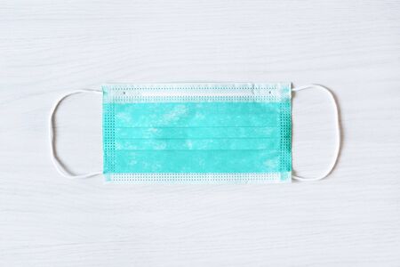 Medical mask for protection against cold and flu or other virus. Surgical protective mask top view. Medical respiratory bandage face on wooden background.の写真素材