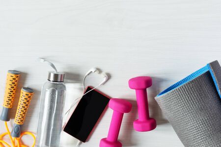 Fitness equipment top view with copy space. Fitness concept. Dumbbells, jump rope, water bottle and...