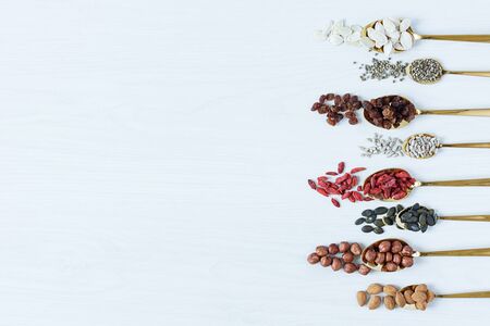 Golden spoons with various superfoods on white wooden background top view. Healthy eating concept. Copy space.の写真素材