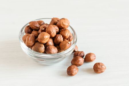 Peeled hazelnuts in glass bowl on white wooden background. Healthy eating concept. Super foods.の写真素材