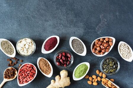 Small white bowls with various superfoods on black background top view. Healthy eating concept. Copy space.の写真素材