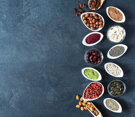 Small white bowls with various superfoods on black background top view. Healthy eating concept. Copy space.の写真素材