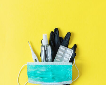 Surgical mask, thermometer, antiseptic and surgical gloves as the virus protection top view on yellow background. Virus illness concept. Cold and flu cure.の写真素材