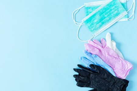 Multi colored latex surgical gloves and surgical masks on blue background top view. Virus protection concept.の写真素材
