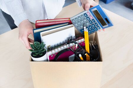 Business woman packing personal company belongings into cardboard box. Dismissal or resignation concept. Company bankruptcy and economy crisis.の写真素材