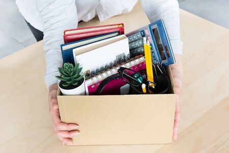 Business woman holding cardboard box with personal company belongings. Dismissal or resignation concept. Company bankruptcy and economy crisis.の写真素材