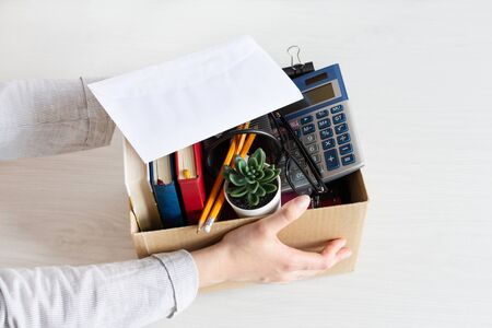 Business woman holding cardboard box with personal company belongings. Dismissal or resignation concept. Company bankruptcy and economy crisis.の写真素材