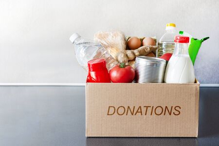 Various food, bottle of oil, milk and water, fresh vegetables in a cardboard box. Food donations or food safe delivery concept. Safe home delivery.の写真素材