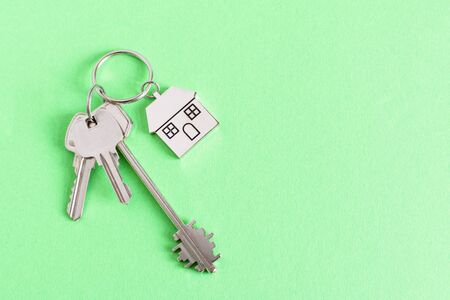 Key and keychain in a house shape on green background top view. Real estate concept. Copy space.の写真素材