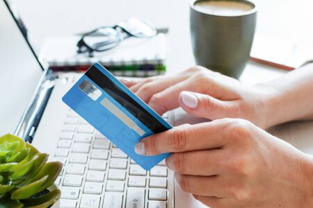 Woman hands holding a credit card and using computer for online shopping entering secure code on...
