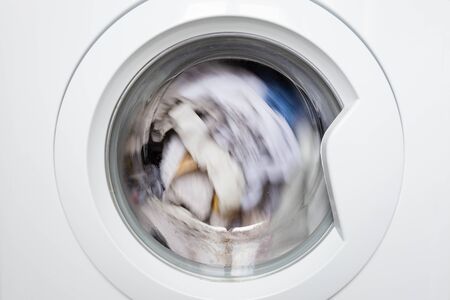 Laundry washing clothes rotating in machine drum front view. Household.の写真素材