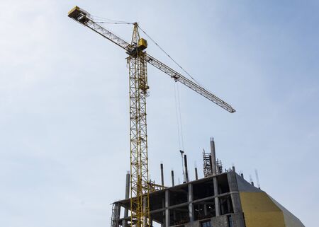 Construction with crane on blue sky background. Crane on construction site.Building being constructed.の写真素材