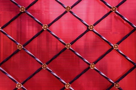 Red plastic fence texture decorated with steel stripes and small gold flowers. Outdoor plastic and steel fence decoration.の写真素材