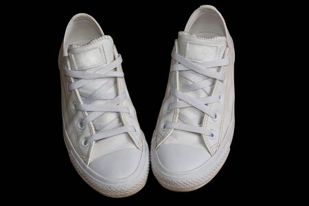 White trendy female leather sneakers closeup isolated on the black background. Woman style casual footwear.の写真素材