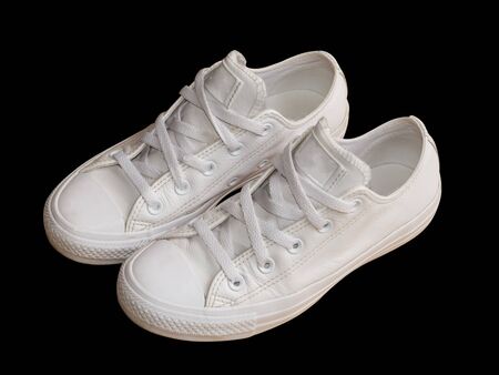 White trendy female leather sneakers closeup isolated on the black background. Woman style casual footwear.の写真素材