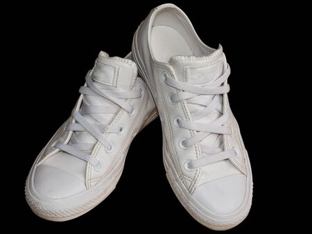 White trendy female leather sneakers closeup isolated on the black background. Woman style casual footwearの写真素材