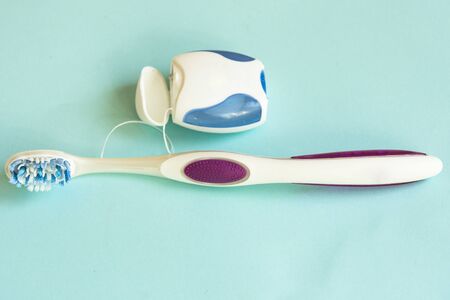 Toothbrush and dental floss on pastel colored background. Copy space.