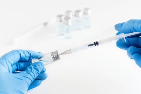 Doctor's hands in a blue gloves holding syringe and vaccine. Immunization concept.の写真素材