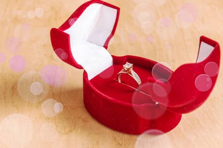 Engagement ring in a gift box on wooden background. Marriage proposal concept.