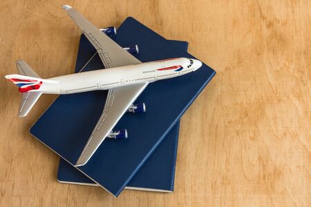 Toy plane and two passports top view on wooden background. Travel concept.