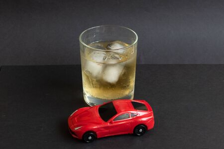 Alcohol and car toy on color background. Driving in a drunken state concept.の写真素材