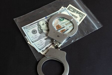 Currency in a plastic package and handcuffs. Physical evidence pack. Criminal illegal money concept.の写真素材