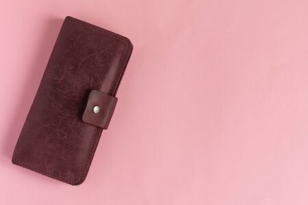 Female wine-colored wallet on pastel pink background. Flat lay. Copy space.の写真素材