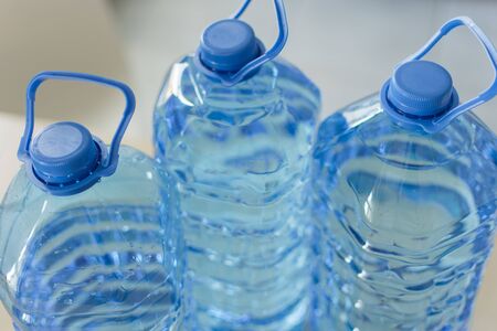 Big plastic bottle with water on the table over bright kitchen backgroung. Bottle of clear...