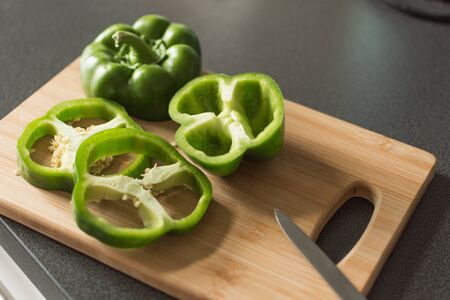 Green pepper cut in half on cutting board top view on black table. Organic green pepper. Healthy eating concept.の写真素材