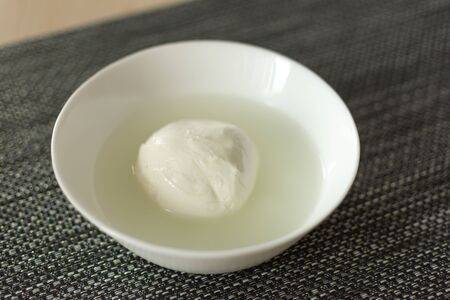 Mozzarella cheese in a bowl with brine. Tasty mozzarella cheese ball. Italian cuisine .
