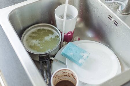 Unwashed dishes and utensils in a kitchen sink. Pile of dirty dishes in a sink. Washing dishes concept.の写真素材
