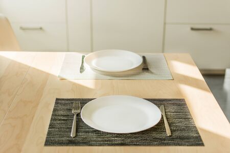Empty plate with fork and knife on wooden table in the kitchen interior. Morning table serving for...