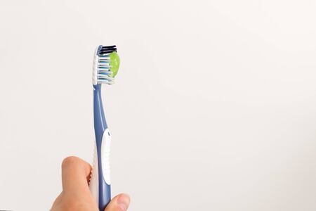 Toothbrush with green toothpaste on white background. Copy space.