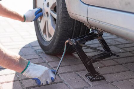 Mechanic changing wheel on car with a wrench outdoor in a sunny day.の写真素材