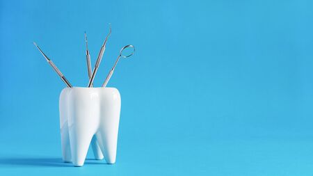 White dental tooth model with dentistry tools for teeth dental care on blue background. Oral dental hygiene concept. Copy space.の写真素材