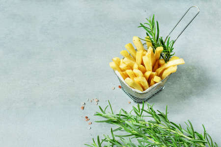 French fries in basket with spices and rosemary on grey background. Copy space.の写真素材