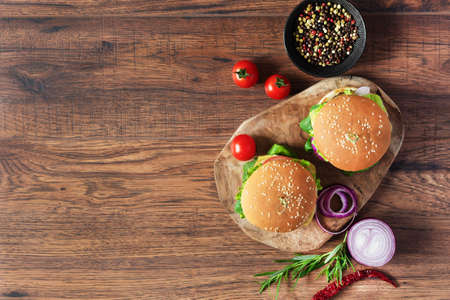 Beef burger with fresh salad, cheese, tomatoes and pepper spice on wooden background top view. Fast food.の写真素材