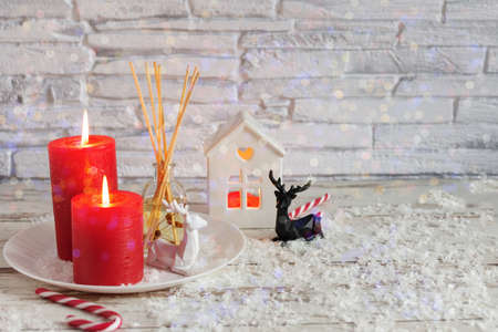 Candles and Christmas decoration on white wooden table with bokeh lights over brick wall. Sweet hime, Christmas time.の写真素材